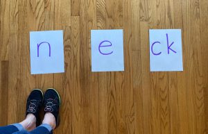 letter cards on the floor spelling "neck"
